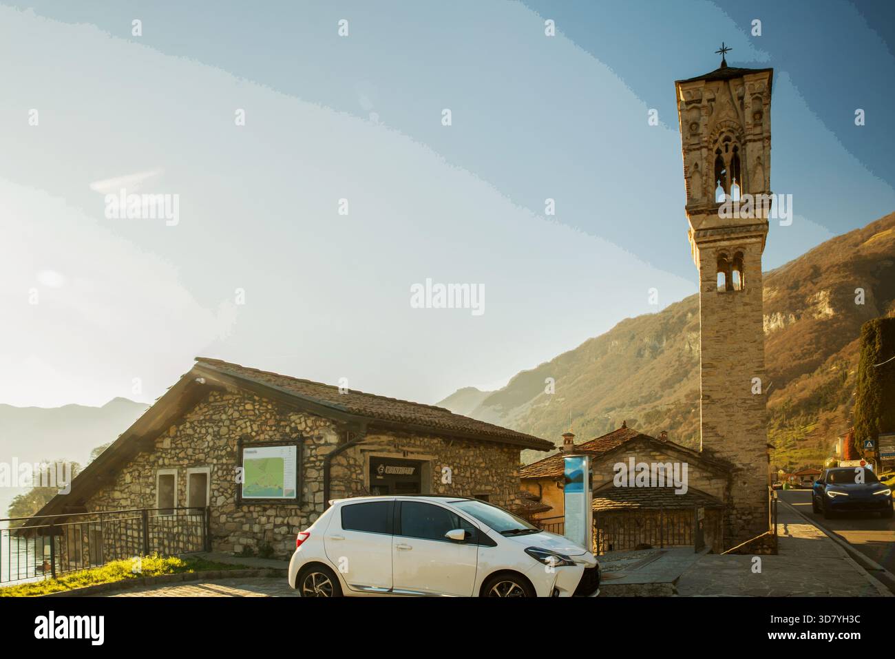 Strada asfaltata lungo la costa da Como a nord e alto campanile di chiesa cattolica. Le persone che si svegliano NOI facciamo anche escursioni con l'etnia cinese Foto Stock