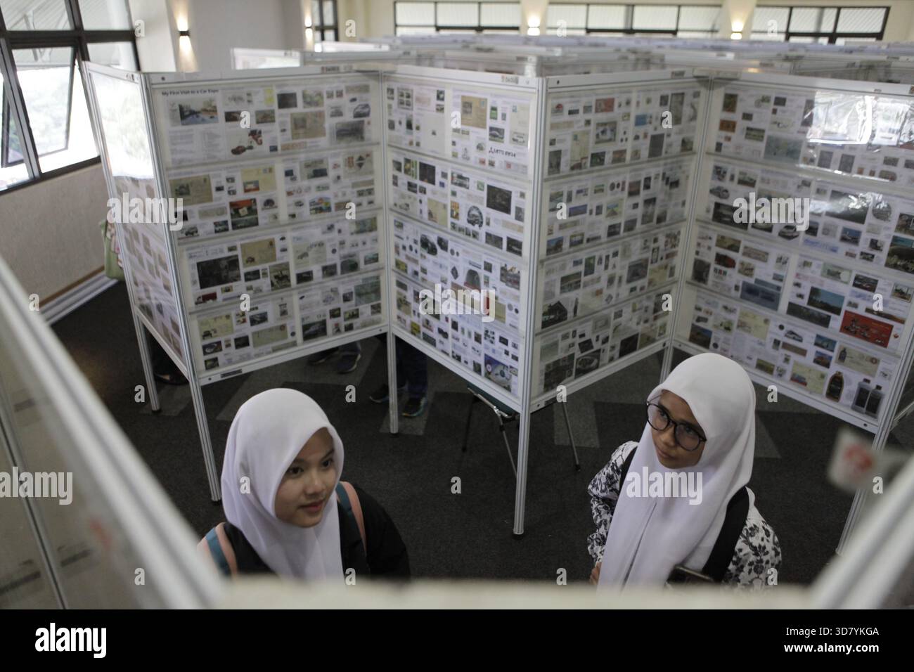 Bandung, Indonesia. 27 novembre 2025. Gli studenti delle scuole superiori osservano le collezioni storiche di francobolli esposte all'International Five Nations Philately Exhibition di Bandung, Indonesia. La mostra espone centinaia di francobolli e cartoline provenienti da cinque paesi del sud-est asiatico e funge da spazio di raccolta per i collezionisti. Presenta anche un viaggio attraverso la storia della comunicazione e la documentazione dell'identità nazionale attraverso gli oggetti postali. (Foto di Ardi Septian/NurPhoto) credito: NurPhoto SRL/Alamy Live News Foto Stock