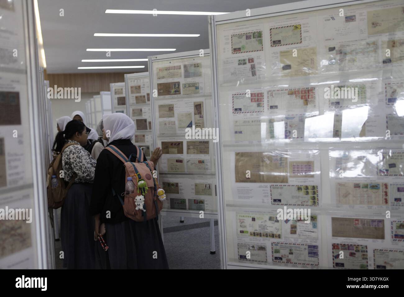 Bandung, Indonesia. 27 novembre 2025. Gli studenti delle scuole superiori osservano le collezioni storiche di francobolli esposte all'International Five Nations Philately Exhibition di Bandung, Indonesia. La mostra espone centinaia di francobolli e cartoline provenienti da cinque paesi del sud-est asiatico e funge da spazio di raccolta per i collezionisti. Presenta anche un viaggio attraverso la storia della comunicazione e la documentazione dell'identità nazionale attraverso gli oggetti postali. (Foto di Ardi Septian/NurPhoto) credito: NurPhoto SRL/Alamy Live News Foto Stock