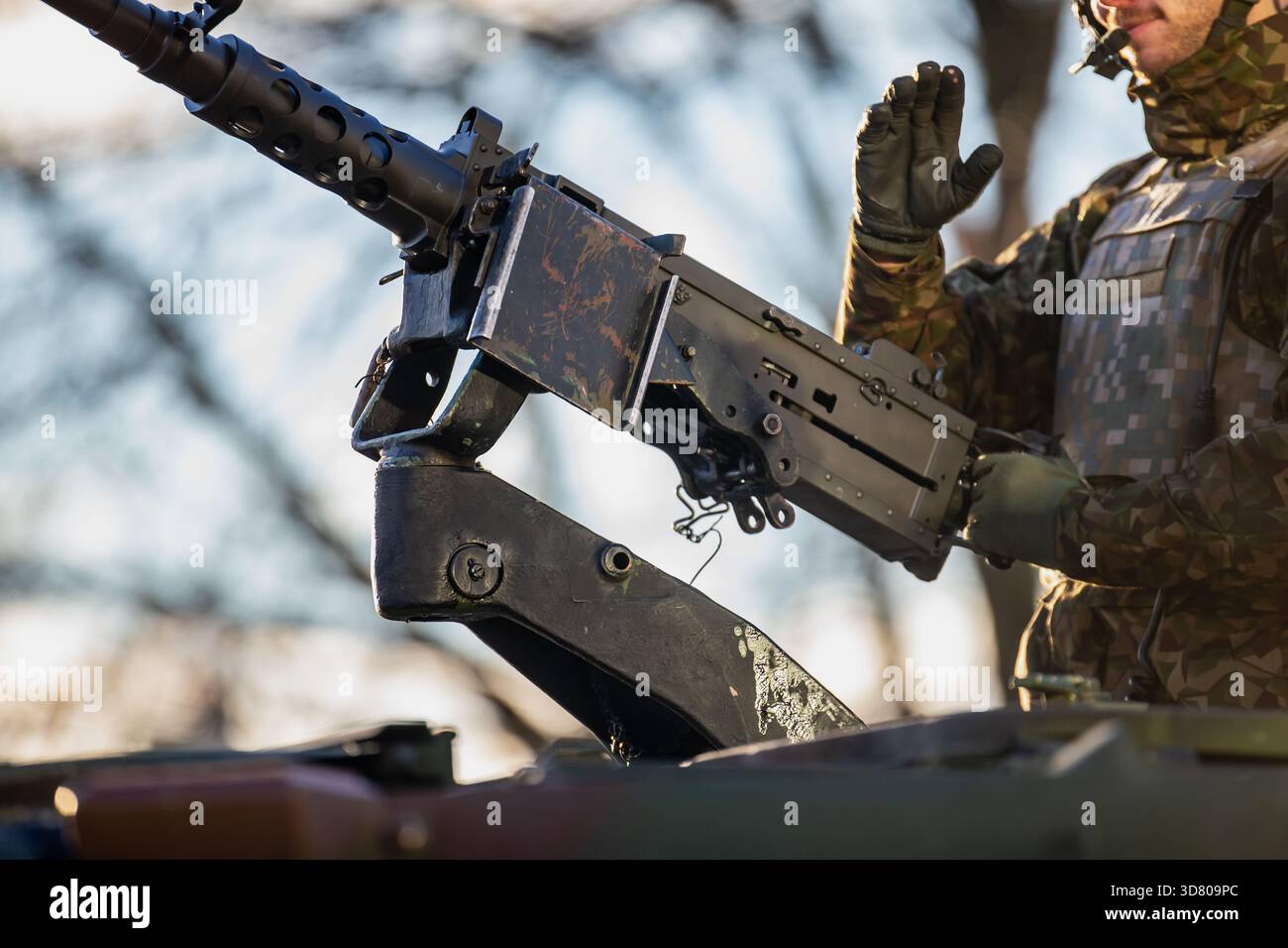 Soldato alleato NATO che opera mitragliatrice pesante montata su veicoli corazzati con meccanismo ad arma visibile, equipaggiamento protettivo e illuminazione invernale durante il periodo d Foto Stock