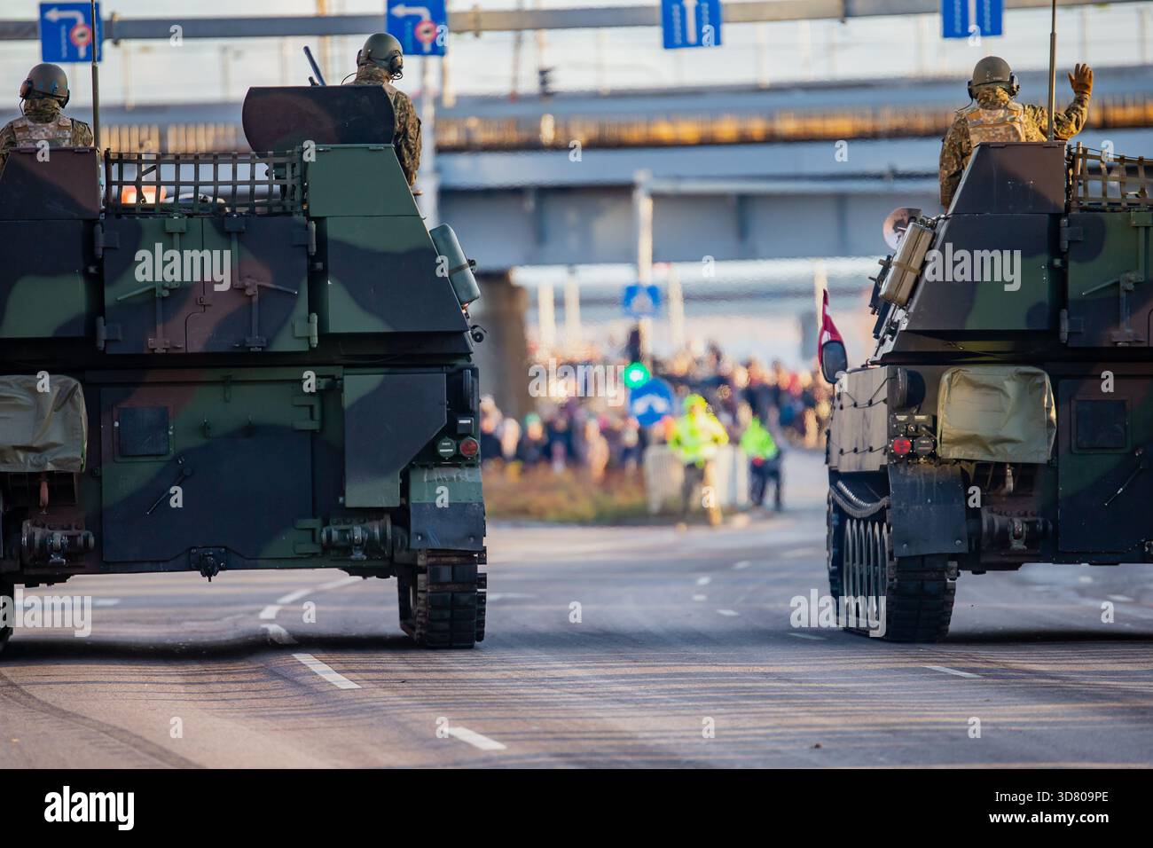 Convoglio militare NATO di portaerei corazzati che mostra soldati, superfici mimetiche e strutture posteriori rinforzate che avanzano attraverso un'area della città durante il def Foto Stock