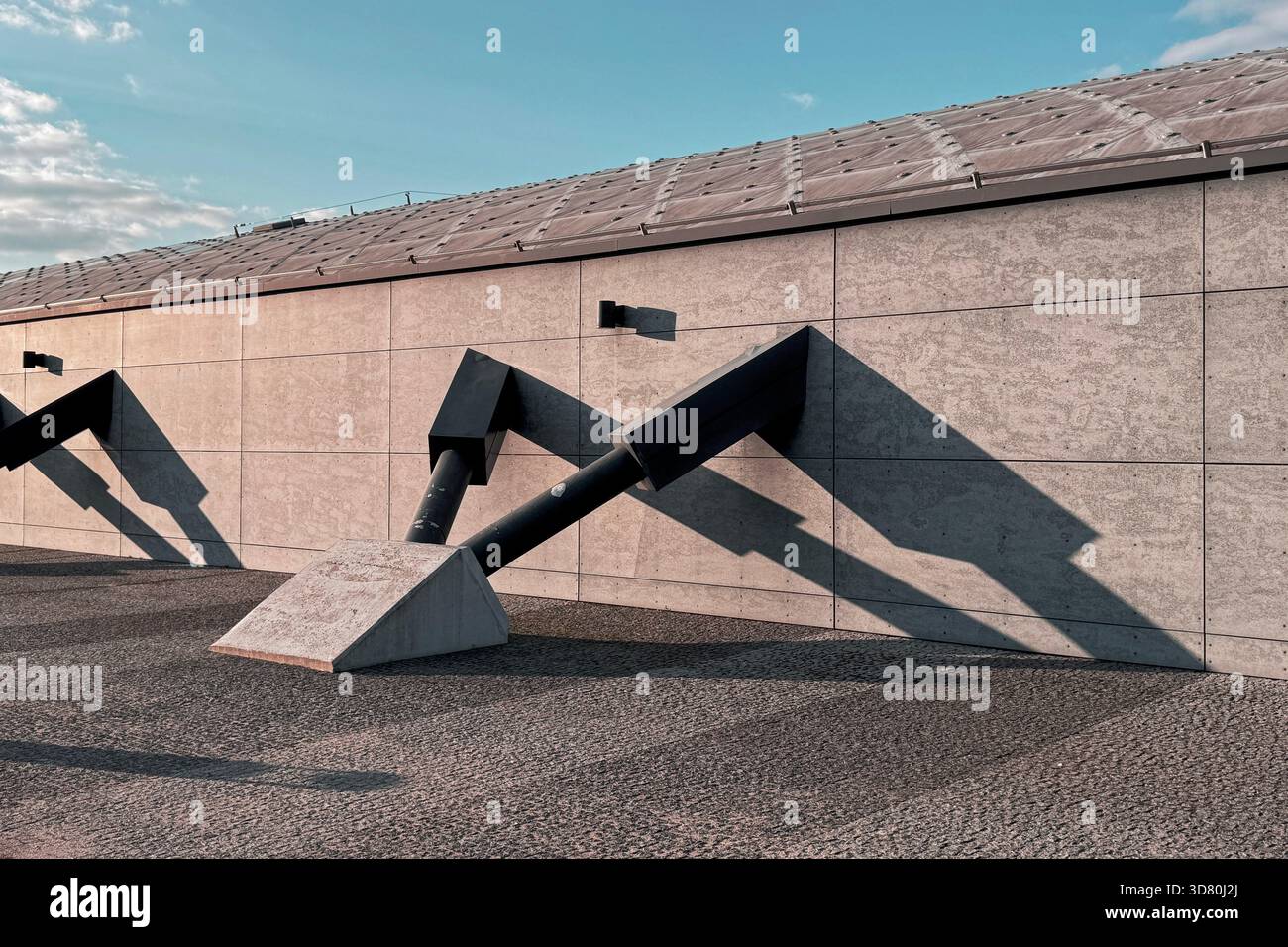 Dettagli architettonici moderni su una facciata di un edificio in cemento sotto un cielo limpido, che getta forti ombre geometriche Foto Stock