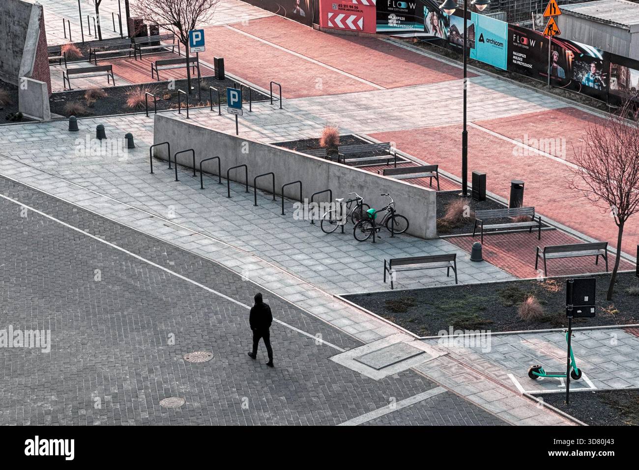 Vista aerea di una piazza urbana minimalista con panche, bancarelle per biciclette, biciclette parcheggiate e un'unica passeggiata pedonale attraverso lo spazio pavimentato. Foto Stock