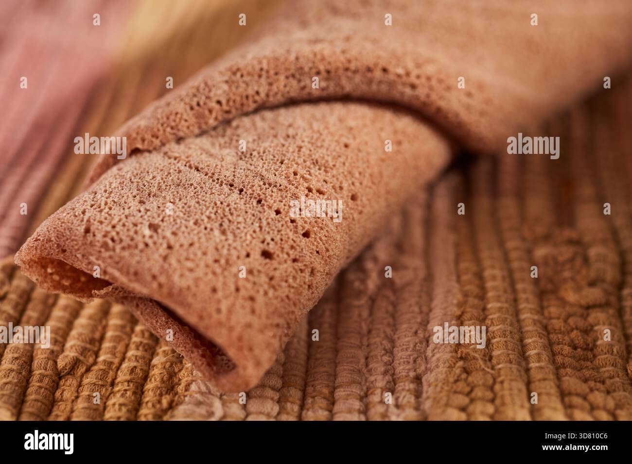 Un pezzo arrotolato di injera, la focaccia etiope a base di teff, una farina locale Foto Stock