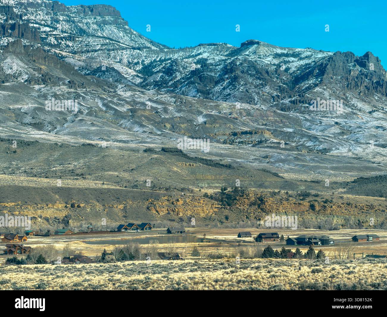 Vista sulla valle abitata di Wapiti a Cody, Wyoming. Montagne alte e aspre ti circondano. È caduta tarda con la prima neve a terra/ Foto Stock