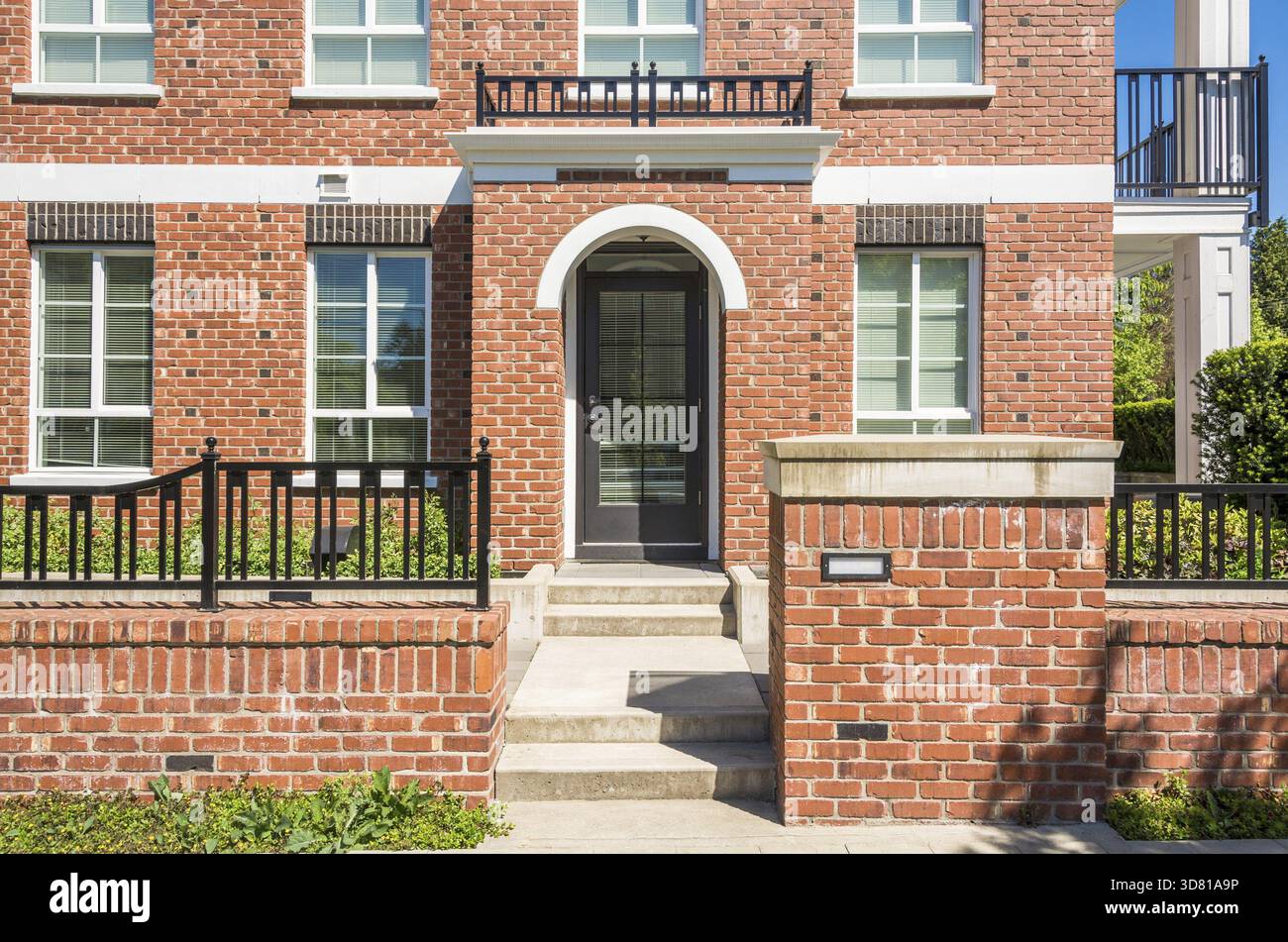 Ingresso di un nuovissimo edificio di appartamenti con porte in cemento e recinzione in mattoni di fronte Foto Stock