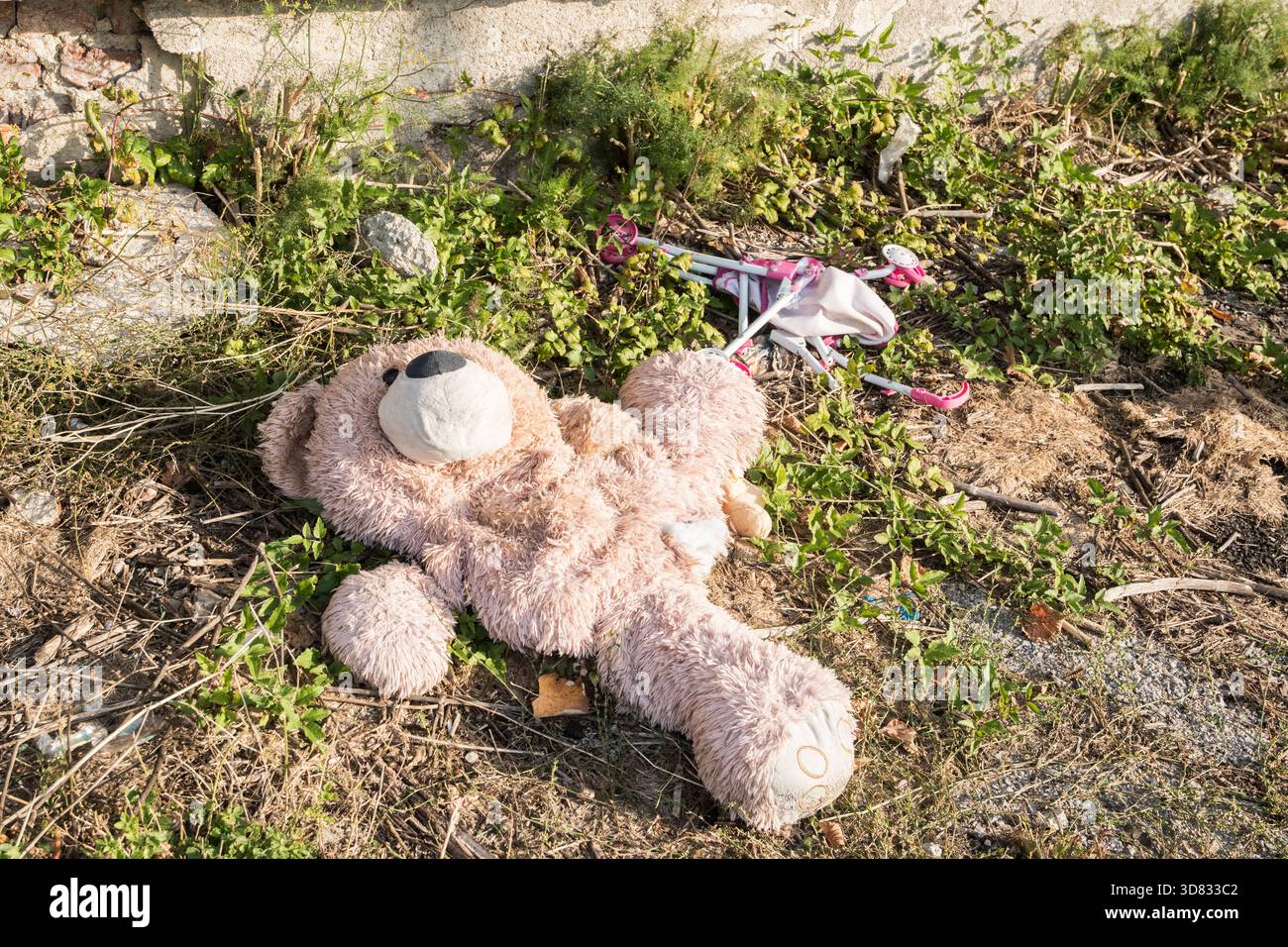 Peluche scartata giace su un terreno accidentato, simboleggiando la perdita, l'abbandono, i ricordi d'infanzia e l'abbandono emotivo Foto Stock