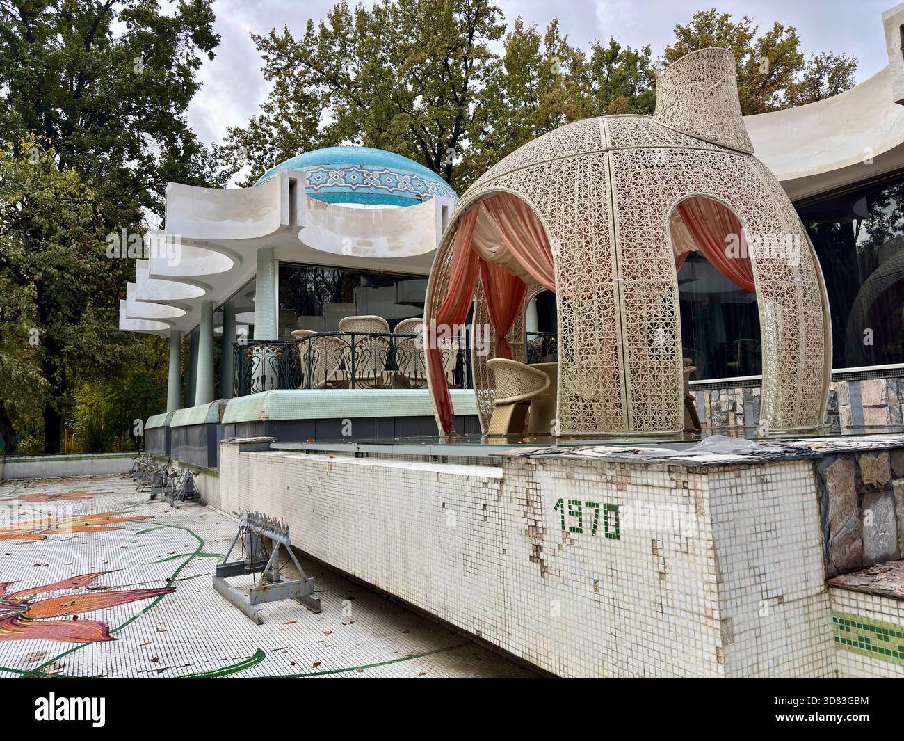 Ristorante abbandonato degli anni '1970 con piscina a mosaico e gazebo in vimini Foto Stock
