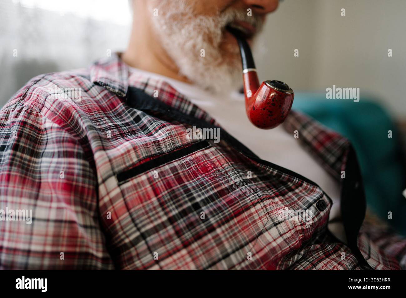 L'anziano ama fumare pipa mentre si rilassa all'interno Foto Stock