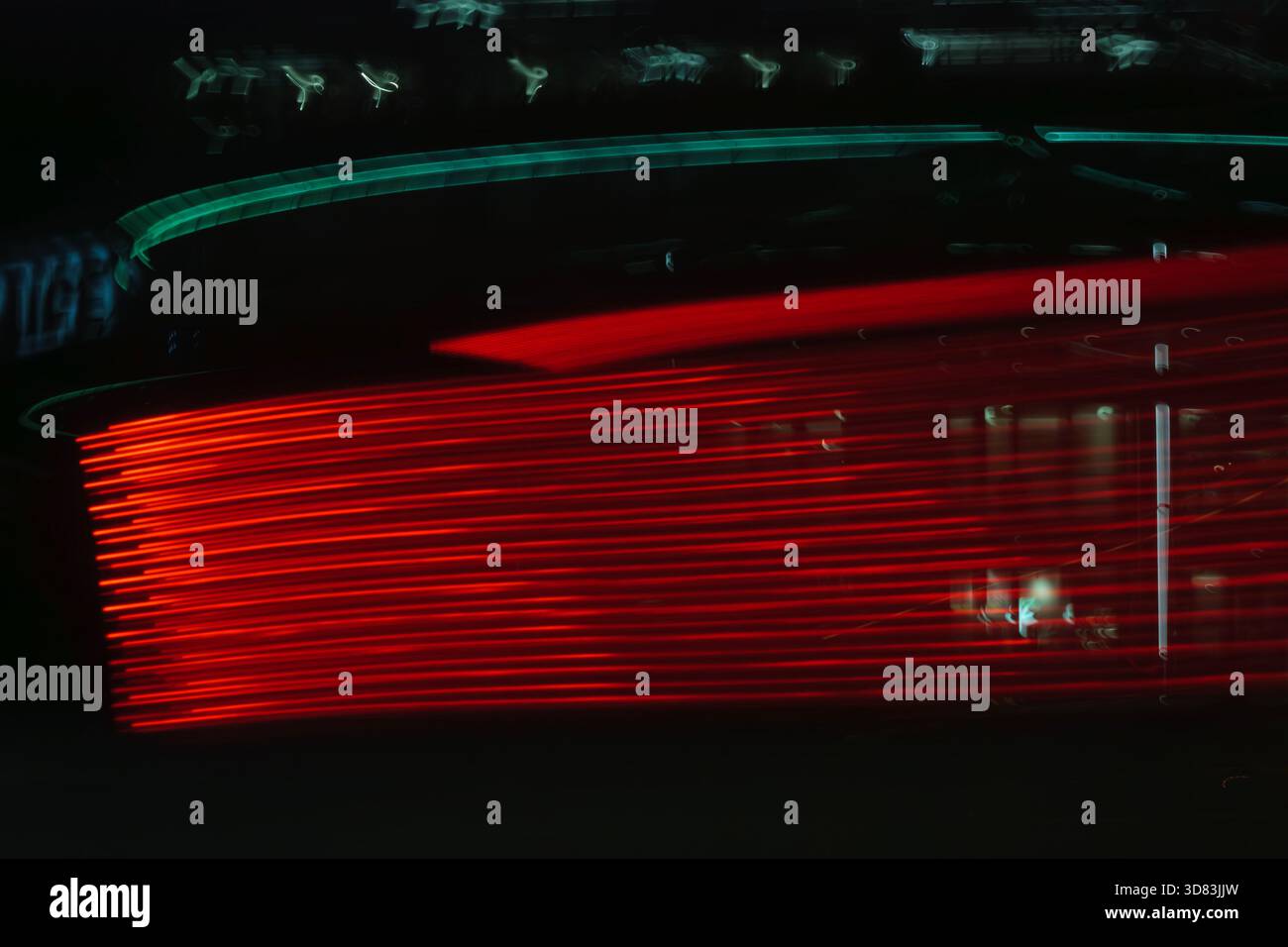 Una lunga esposizione di luci rosse di coda per auto che creano un senso di velocità e movimento su una strada buia. Foto Stock