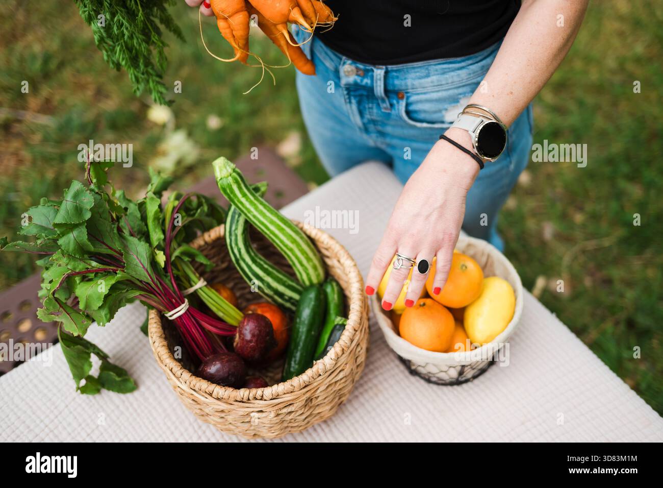 Mani con prodotti su cesti di carote, verdure e agrumi Foto Stock