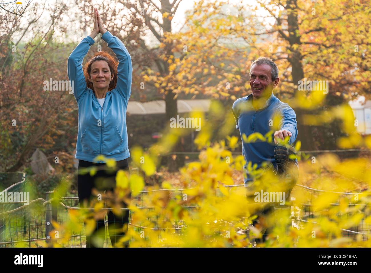 Coppie mature che praticano yoga stretching all'aperto nel parco autunnale Foto Stock