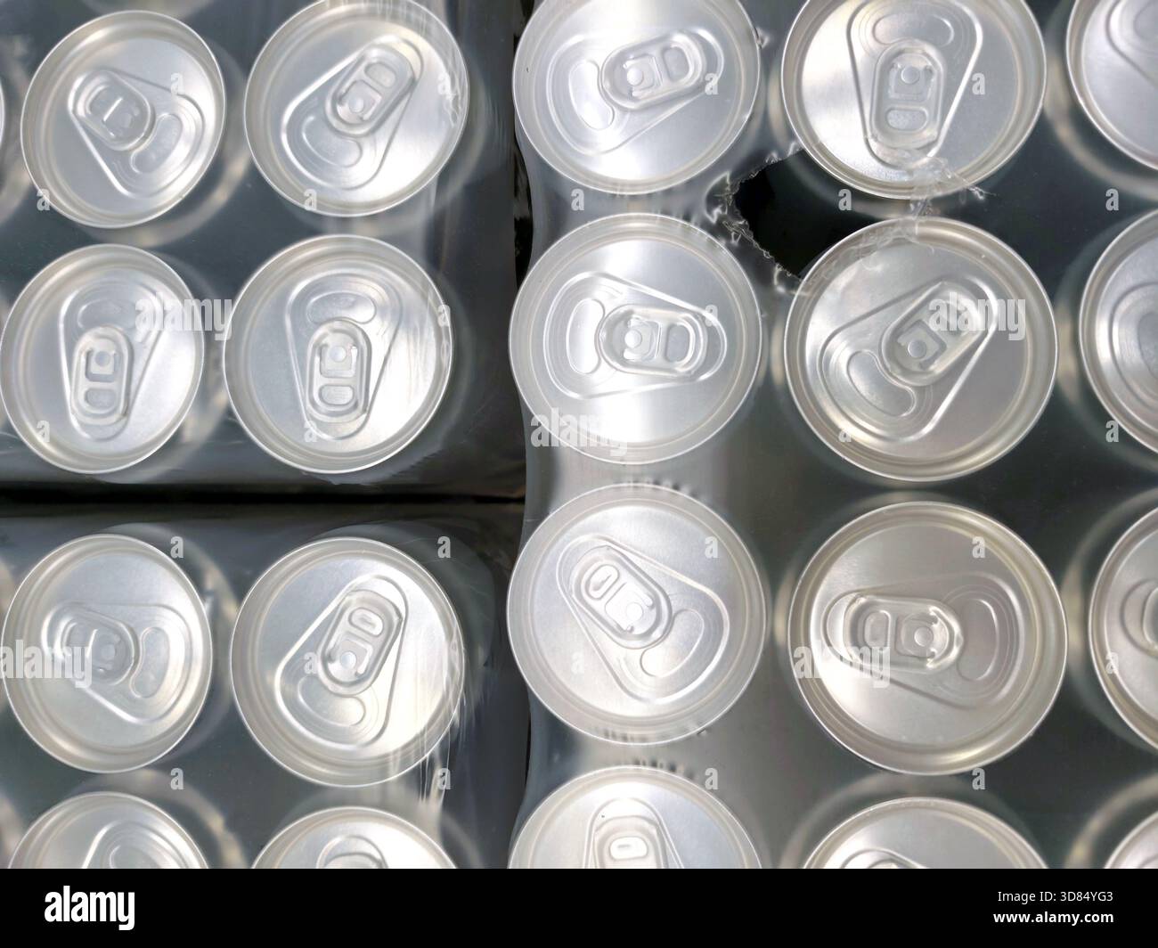 Vista dall'alto delle lattine in alluminio ben confezionate in pellicola termoretraibile. modello ripetitivo di canottiere, industria delle bevande, produzione di massa e riciclaggio. Foto Stock
