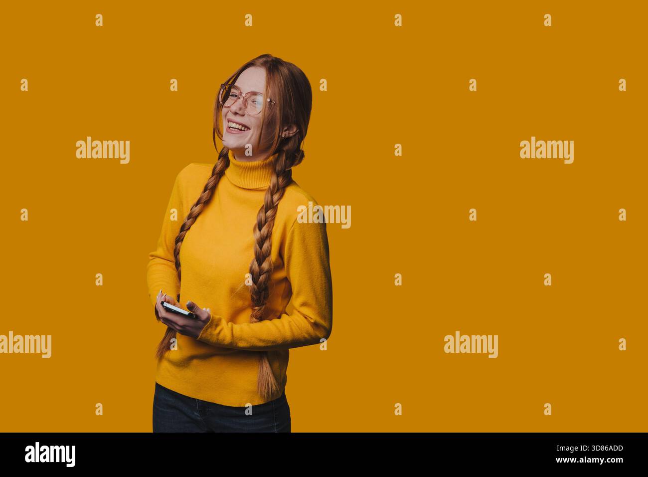 Donna rilassata che indossa un maglione giallo che interagisce con il suo telefono Foto Stock