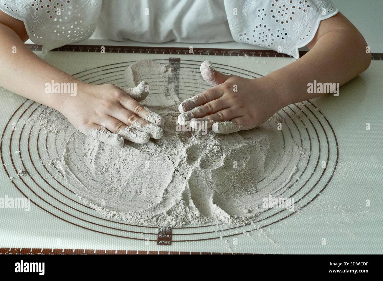 Le mani dei bambini impastano l'impasto su un tavolo in cucina Foto Stock