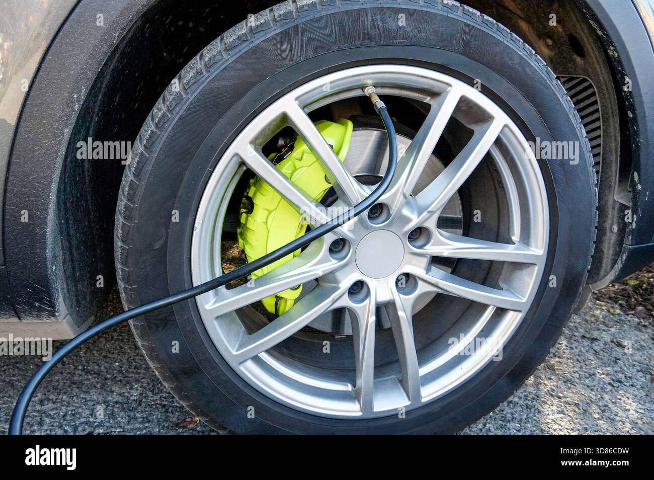 Primo piano della ruota di un'auto con un cavo elettrico. Foto Stock