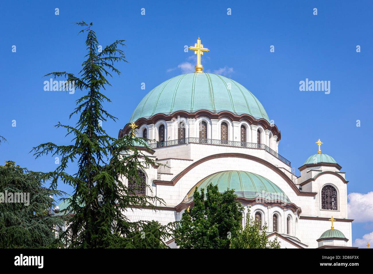 Chiesa di San Sava, Chiesa ortodossa serba a Belgrado, Serbia, con facciata in marmo bianco, grande cupola verde e croce placcata oro contro la S blu Foto Stock