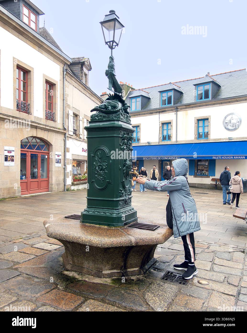 Donna si lava le mani in una fontana pubblica ornamentale a Concarneau, Bretagna, Francia Foto Stock