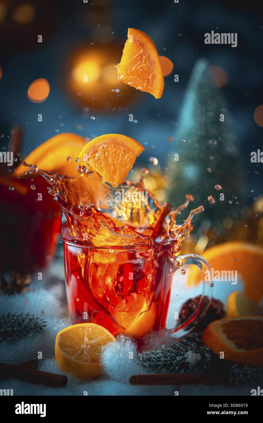Il VIN brulé viene spruzzato da un bicchiere con una fetta di arancia cadente e un'atmosfera invernale Foto Stock