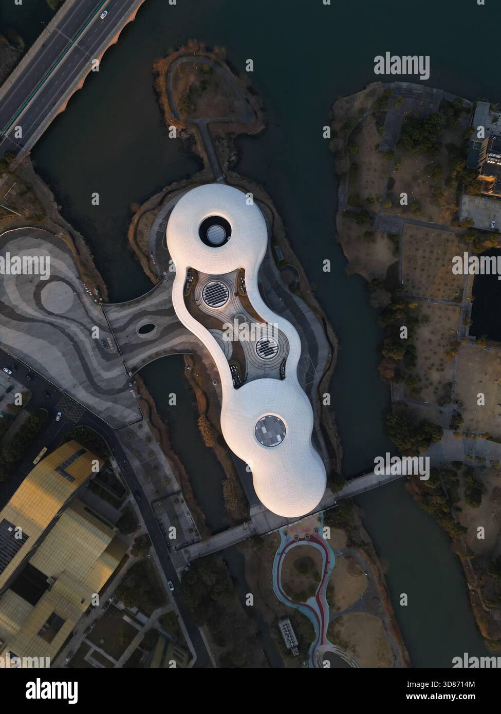 Vista aerea dell'edificio dalla forma unica circondato dall'acqua, con le sue curve bianche che contrastano con l'acqua scura, Hangzhou, Zhejiang, Cina. Foto Stock