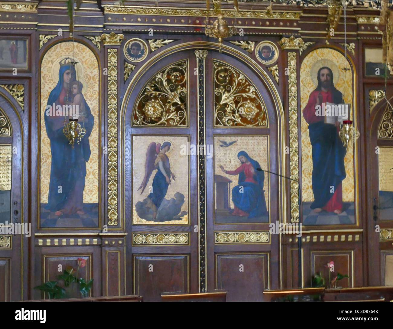 Un'elaborata iconografia religiosa con Madonna con bambino, Gesù Cristo, un angelo e una donna che prega adorna i pannelli della chiesa in legno, creando una spirale Foto Stock