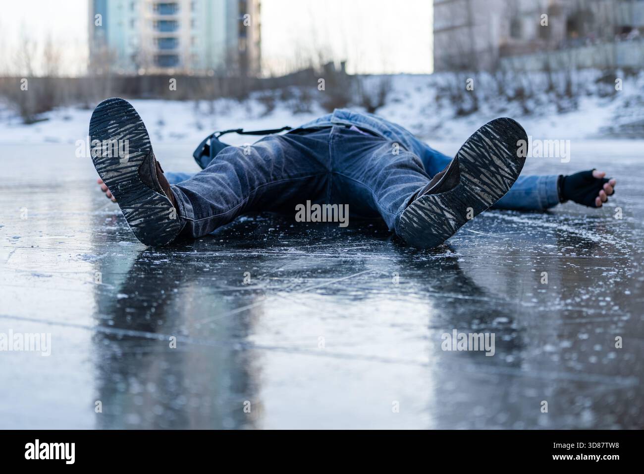L'uomo scivola e cade su un terreno ghiacciato, illustrando il pericolo del ghiaccio invernale e l'elevato rischio di incidenti in condizioni di ghiaccio. Foto Stock
