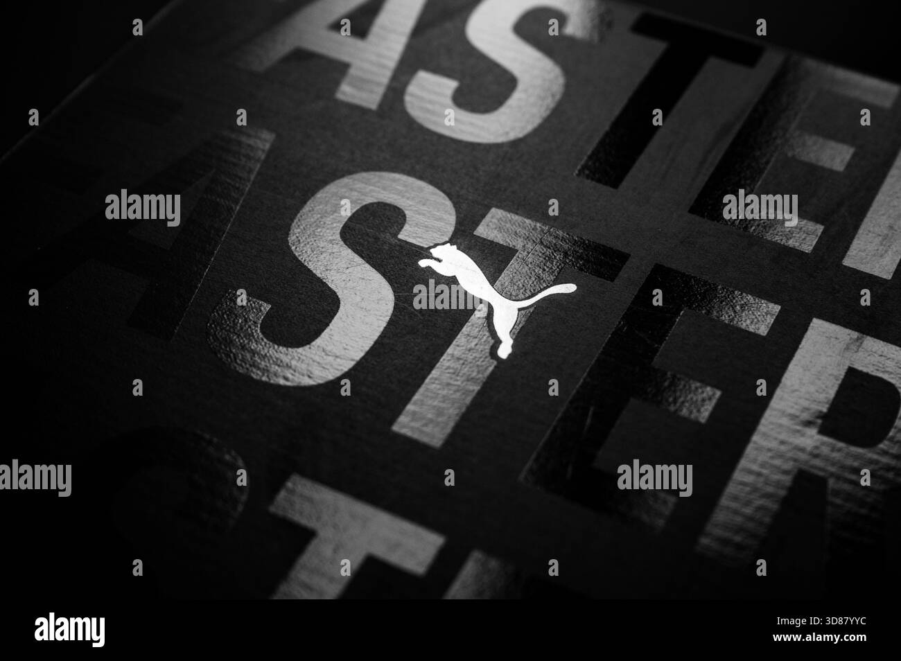BERLINO, GERMANIA, 29. NOVEMBRE 2025: Logo Puma illuminato con una luce riflessa "più veloce" su uno sfondo scuro profondo in una promozione audace e di grande impatto Foto Stock