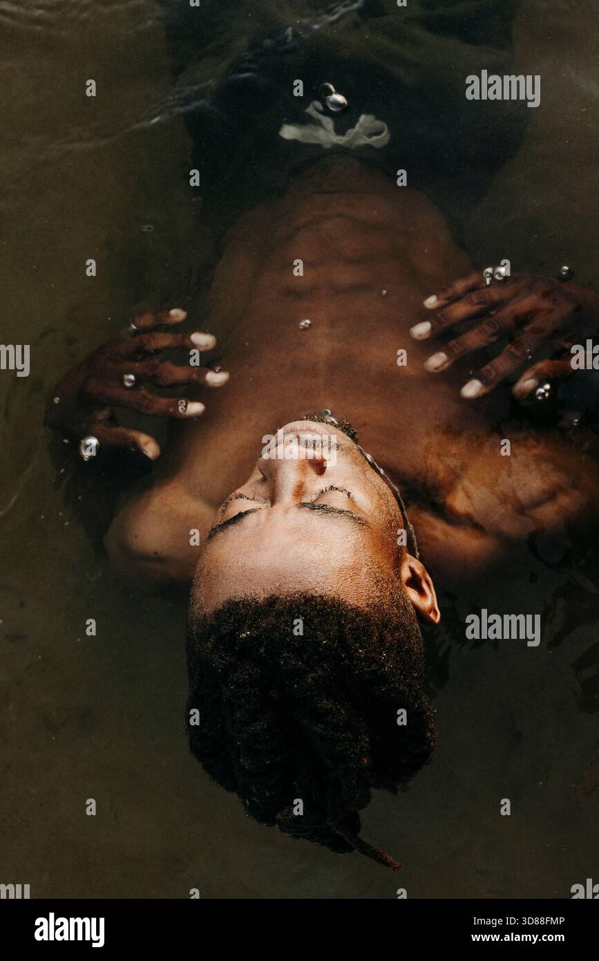 Visuale ad angolo elevato dell'uomo spensierato in acqua con gli occhi chiusi Foto Stock