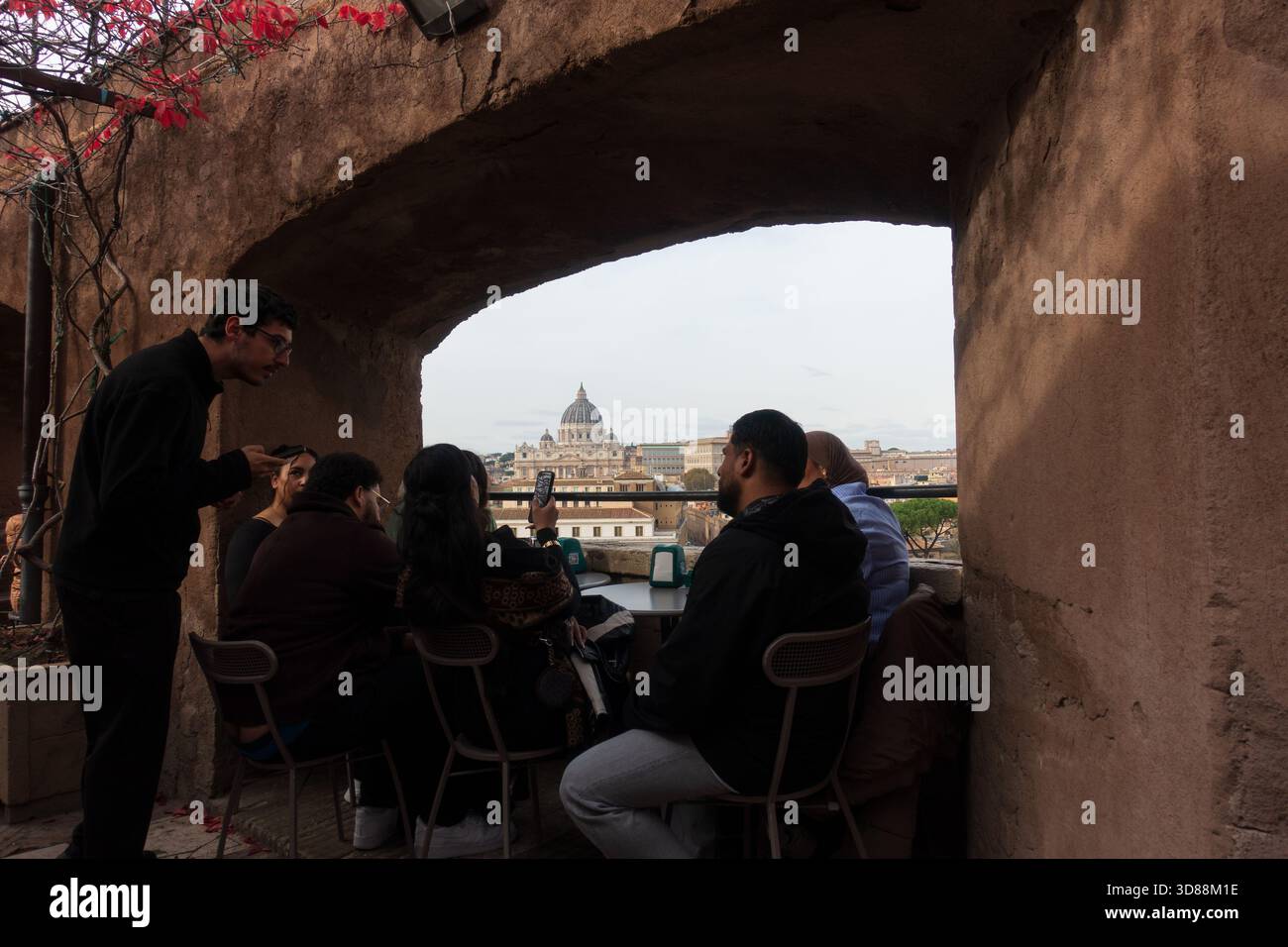 Un gruppo di persone è seduto a un tavolo al bar del castello Sant'Angelo a Roma, affacciato sulla Basilica di San Pietro nella città del Vaticano Foto Stock