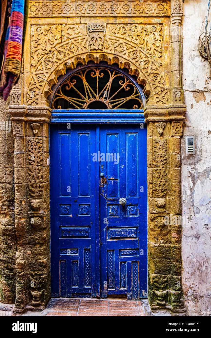 Porta blu ornata con elaborate pietre islamiche scolpite e arco decorativo nella medina di Essaouira, Marocco Foto Stock