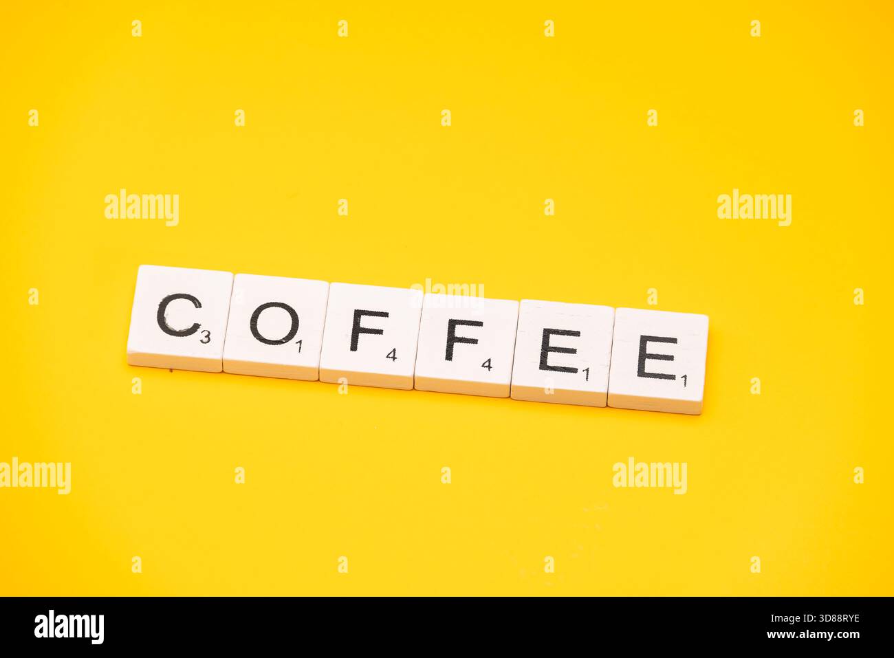 La parola CAFFÈ è stata scritta con tessere su sfondo giallo brillante. Foto Stock