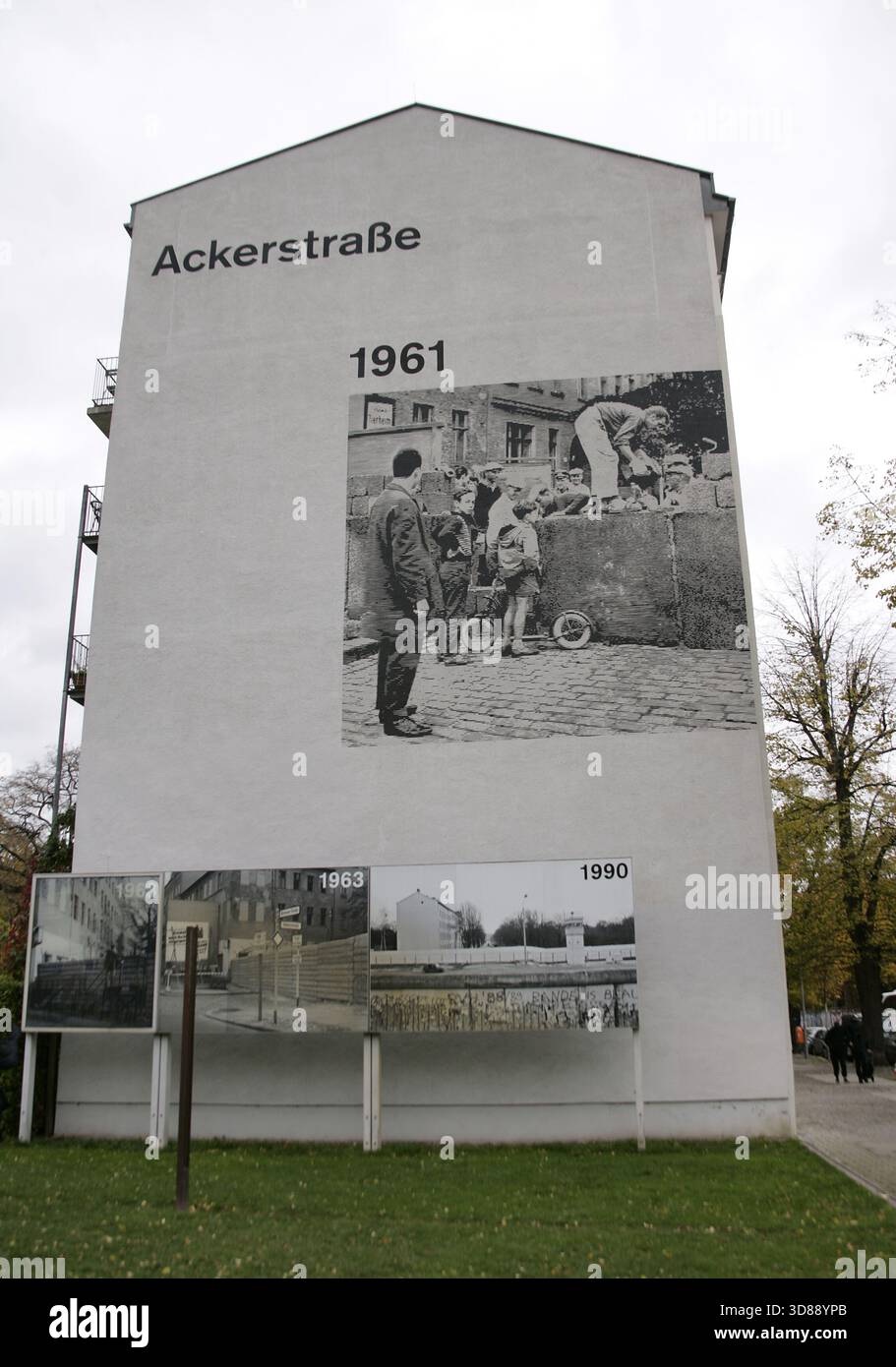 Muro di Berlino, Germania. La sua costruzione iniziò il 13 agosto 1961 e cadde il 9 novembre 1989. Il governo della Repubblica Democratica tedesca (RDT) costruì questa barriera, lunga più di 150 km, per isolare completamente Berlino Est dal resto della RDT. Memoriale del muro di Berlino su Bernauer Strasse. Edificio all'angolo di Ackerstrasse. Pannelli con fotografie storiche che mostrano la costruzione e le sezioni del muro. Dopo la costruzione del muro, la polizia della Germania Est chiuse a chiave le porte esistenti su Bernauer Strasse. Le finestre delle case furono gradualmente murate dopo diversi berlinesi u Foto Stock
