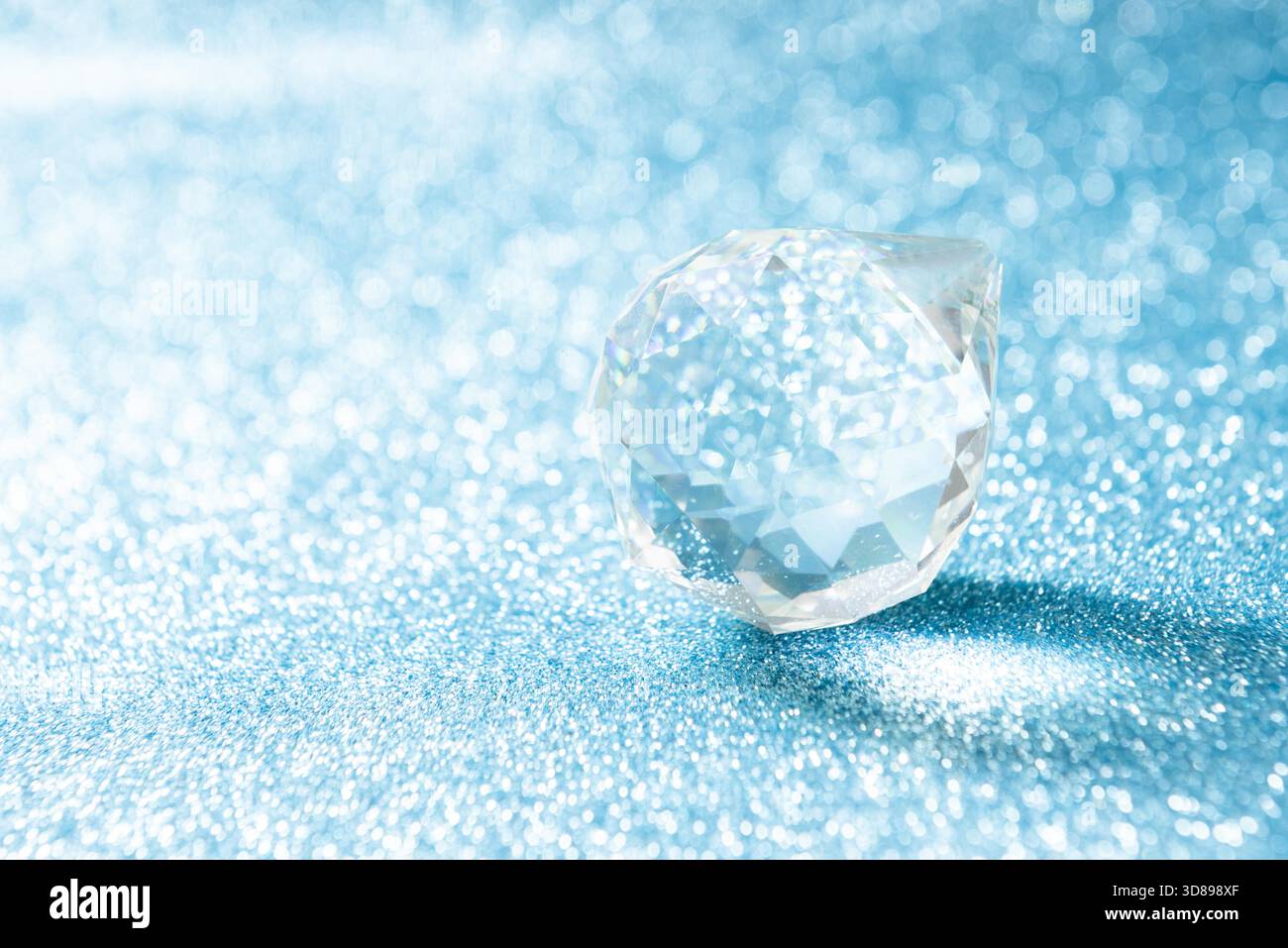 Cristallo trasparente a forma di palla su sfondo blu brillante con bokeh Foto Stock