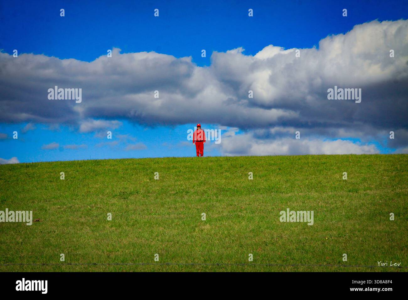 Una persona in rosso si trova in cima a una collina. Foto Stock