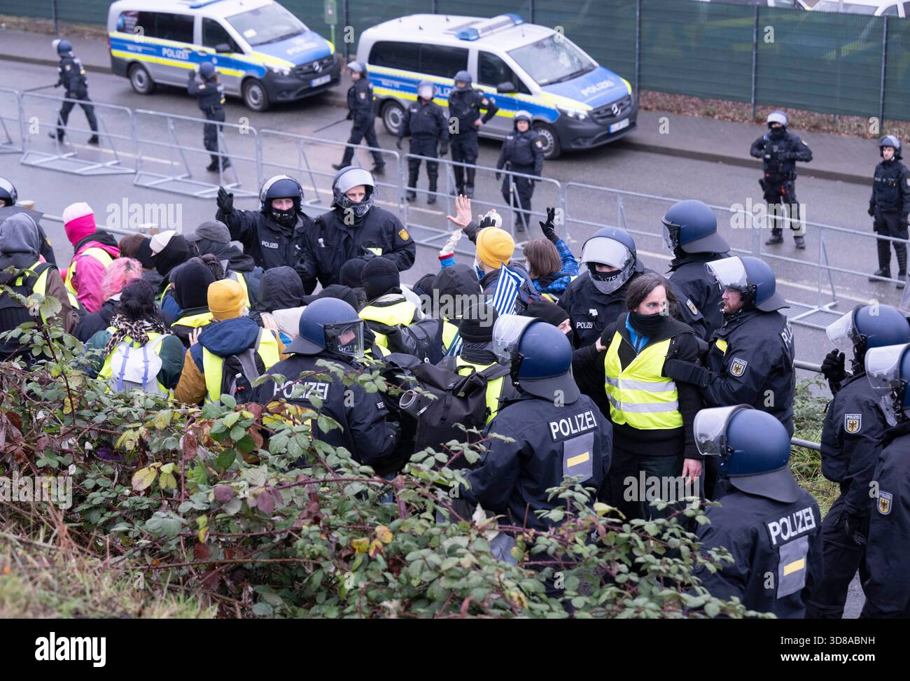 29 novembre 2025, Assia, Gießen: Gli agenti di polizia circondano un gruppo di manifestanti vicino alla sala riunioni. Diverse migliaia di manifestanti hanno protestato contro la fondazione di una nuova organizzazione giovanile AfD sabato. Il suo predecessore, Junge alternative, che era stato classificato come estremista di destra, si era dissolto. Foto: Boris Roessler/dpa Foto Stock