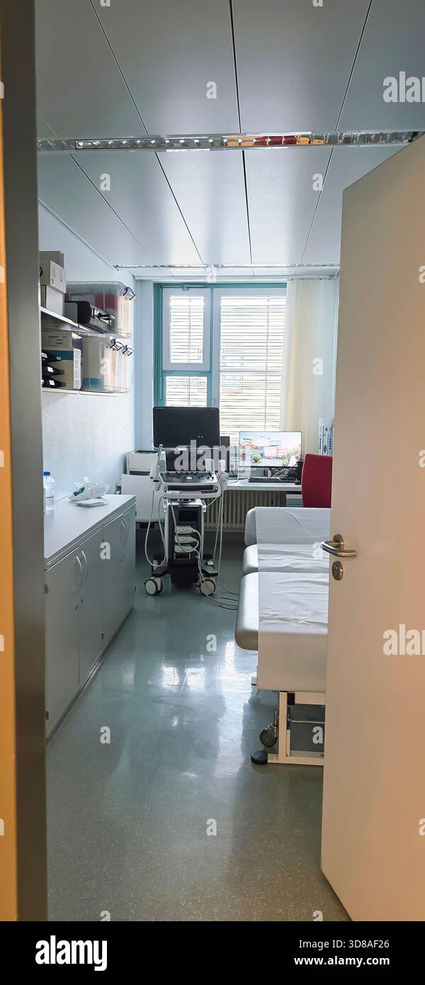 Belin, Germania - 30 maggio 2025: Sala visite mediche dotata di tavoli per trattamenti e attrezzature avanzate in clinica. Ospedale - Immagine stock catturata con smartphone
