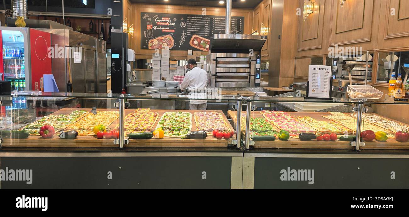 Berlino, Germania - 17 settembre 2025: . Lo chef prepara una deliziosa pizza in un ristorante vivace con condimenti colorati - Immagine stock catturata con smartphone