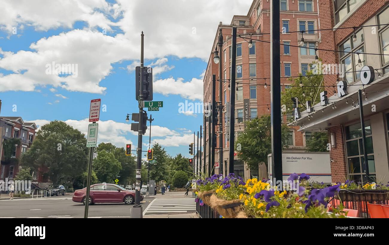 Washington D.C., USA, 24 maggio 2025. I fiori fiancheggiano il marciapiede vicino al ristorante Alero su U Street NW, circondato da edifici in mattoni rossi e cartelli stradali Foto Stock