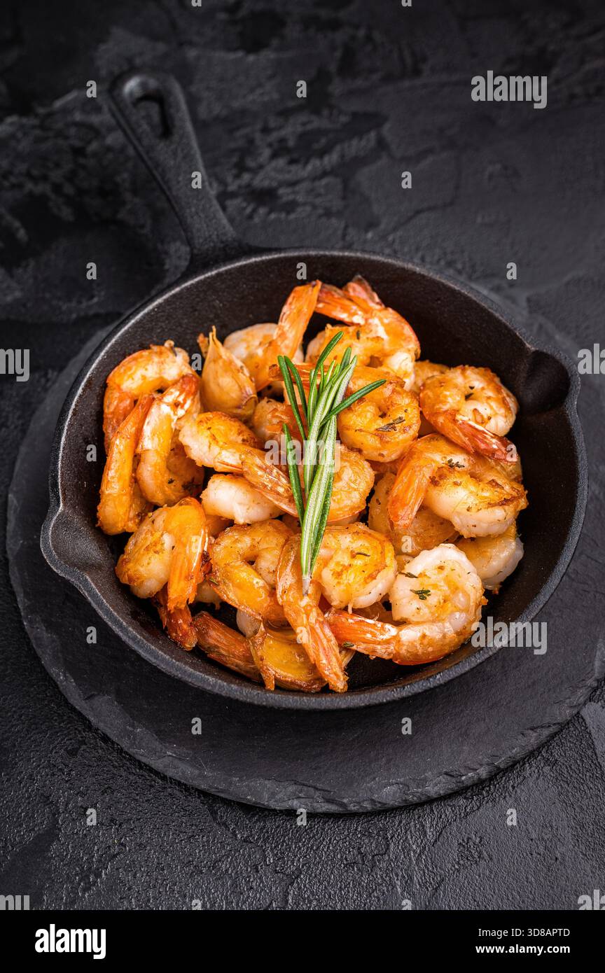 Primo piano di succosi gamberi grigliati guarniti con erbe aromatiche, una deliziosa delizia di pesce per qualsiasi piatto gourmet. sfondo nero. vista dall'alto. Foto Stock