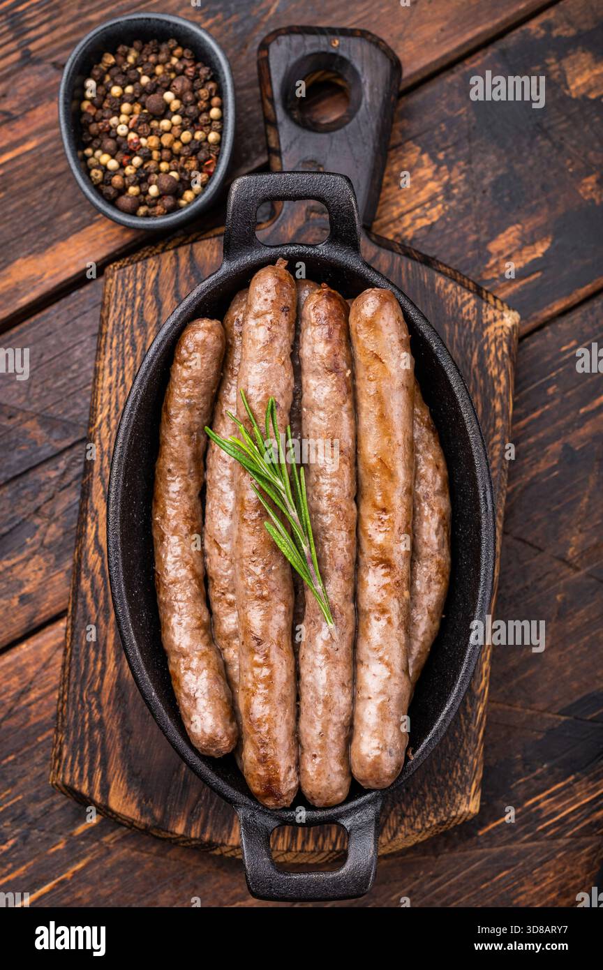 Deliziosa salsiccia alla griglia servita con erbe fresche, un'appetitosa aggiunta a qualsiasi picnic o festa sul cortile. sfondo in legno. vista dall'alto. Foto Stock