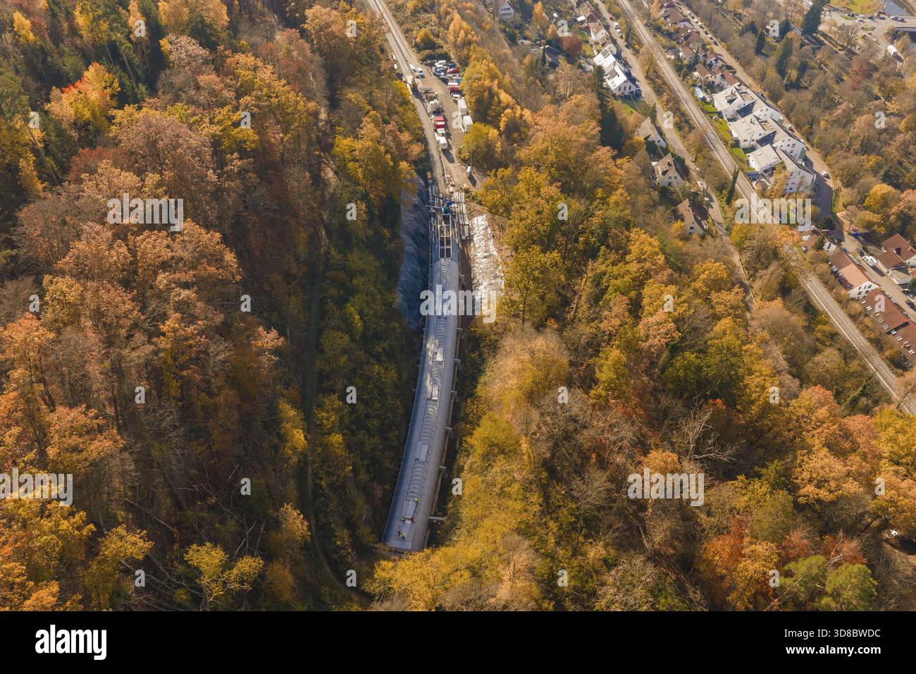 Veduta aerea di un cantiere in una colorata foresta autunnale con strade e case adiacenti, il cantiere della galleria di pipistrelli della Hermann Hesse Railway, Calw Foto Stock