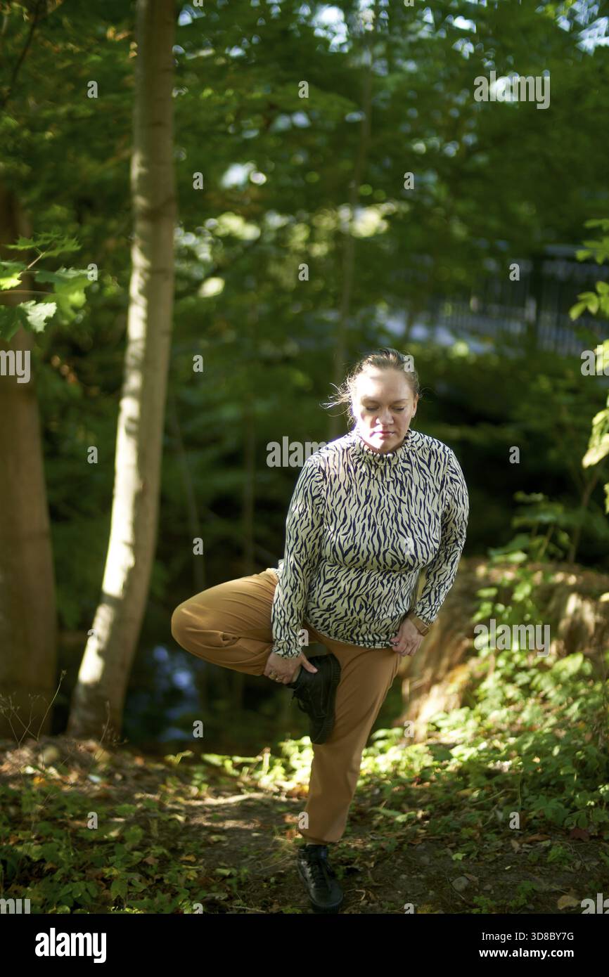Donna Ucraina attenta che fa esercizio di yoga in natura, trova stabilità nel proprio atteggiamento, tranquillità, calma, calma, natura, park, allenamento Foto Stock