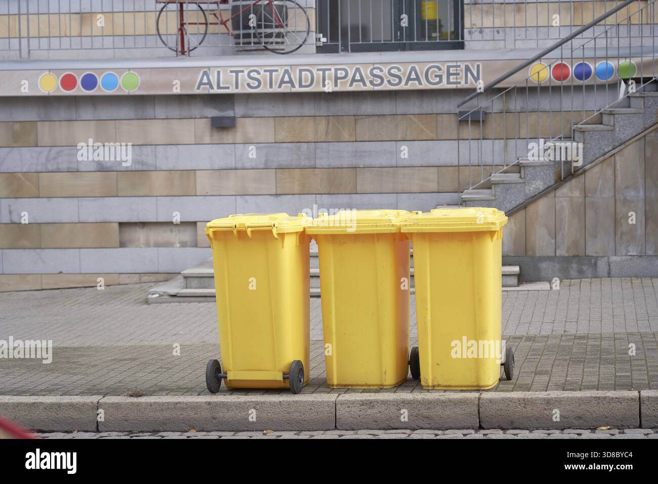 Taniche gialle per rifiuti provenienti dallo smaltimento di materiali plastici, metallici o compositi di fronte ai corridoi della città vecchia, come simbolo del centro storico Foto Stock