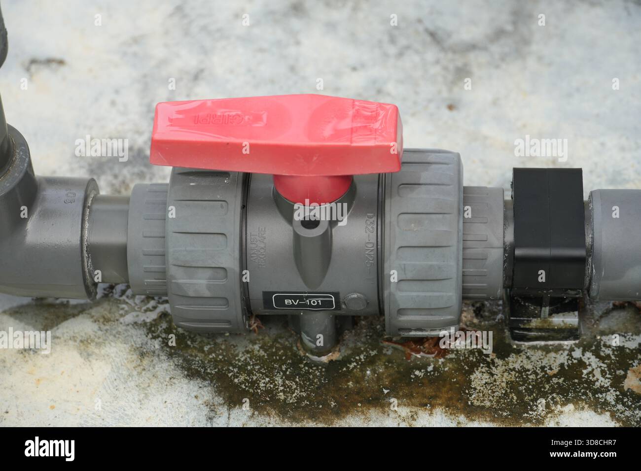 Esaminate le tubazioni robuste con un tubo grigio e un manico rosso brillante, ideali per le applicazioni industriali che richiedono un controllo e una distribuzione dell'acqua affidabili Foto Stock