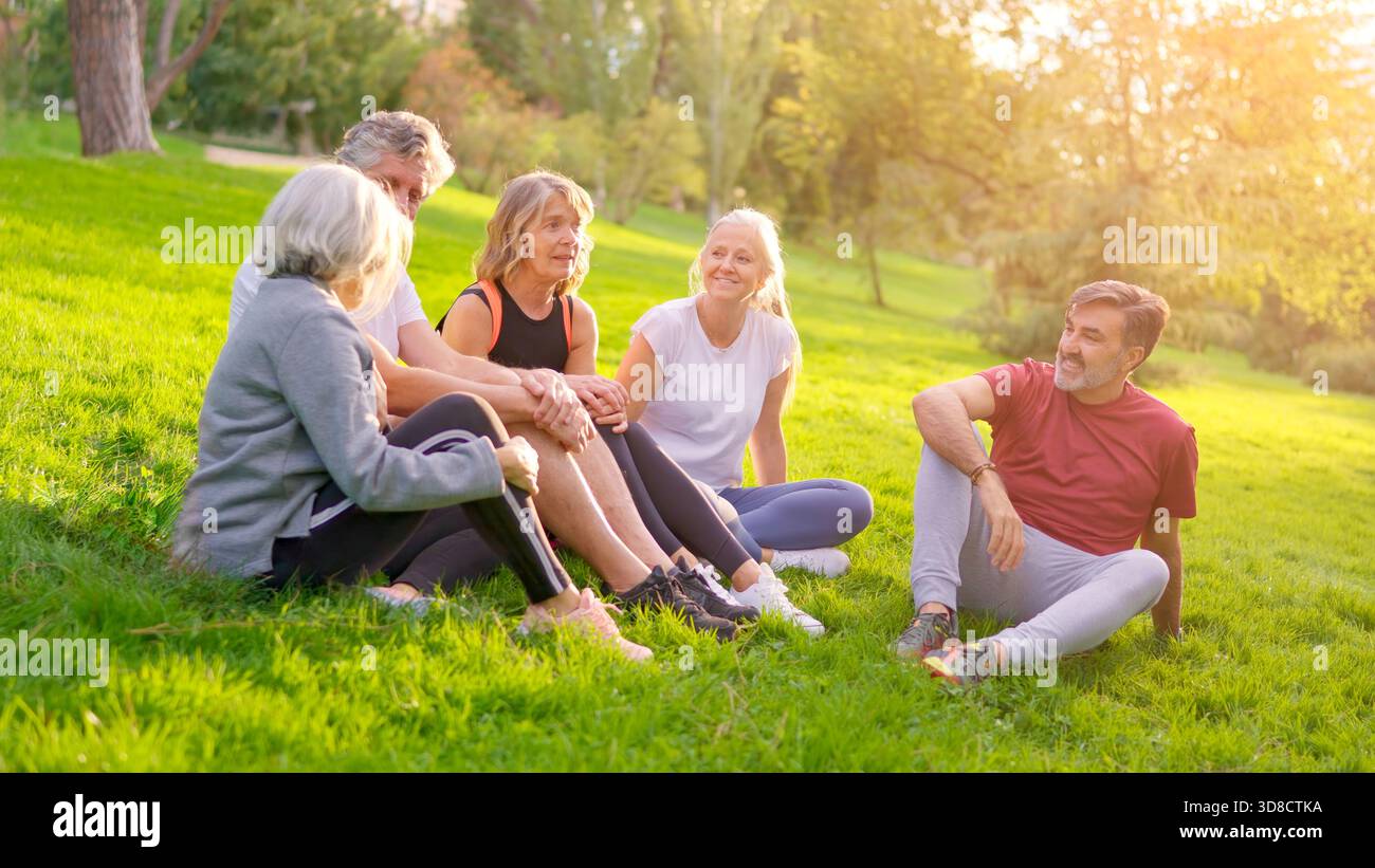 Amici anziani che parlano insieme dopo essersi allenati nel parco Foto Stock