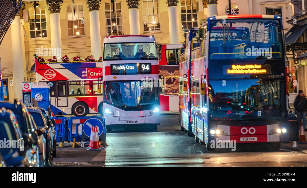 Festosa scena di strada londinese con tre autobus a due piani, luci natalizie e atmosfera serale della città. Foto Stock