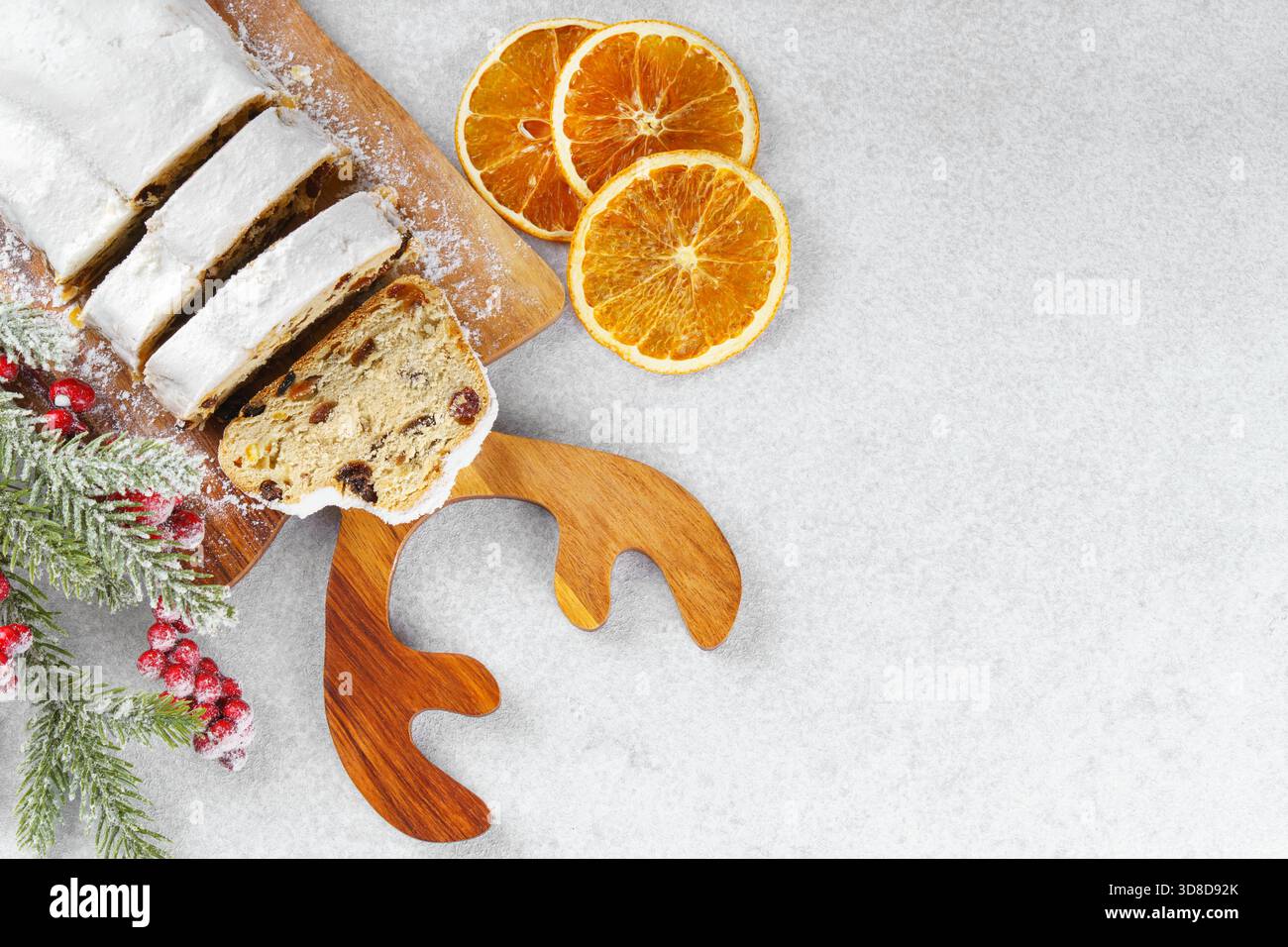 Tradizionale panino natalizio, pane di frutta dolce a fette su tavola di legno, spolverato con zucchero a velo su sfondo bianco testurizzato, spazio copia. Spezie, d Foto Stock