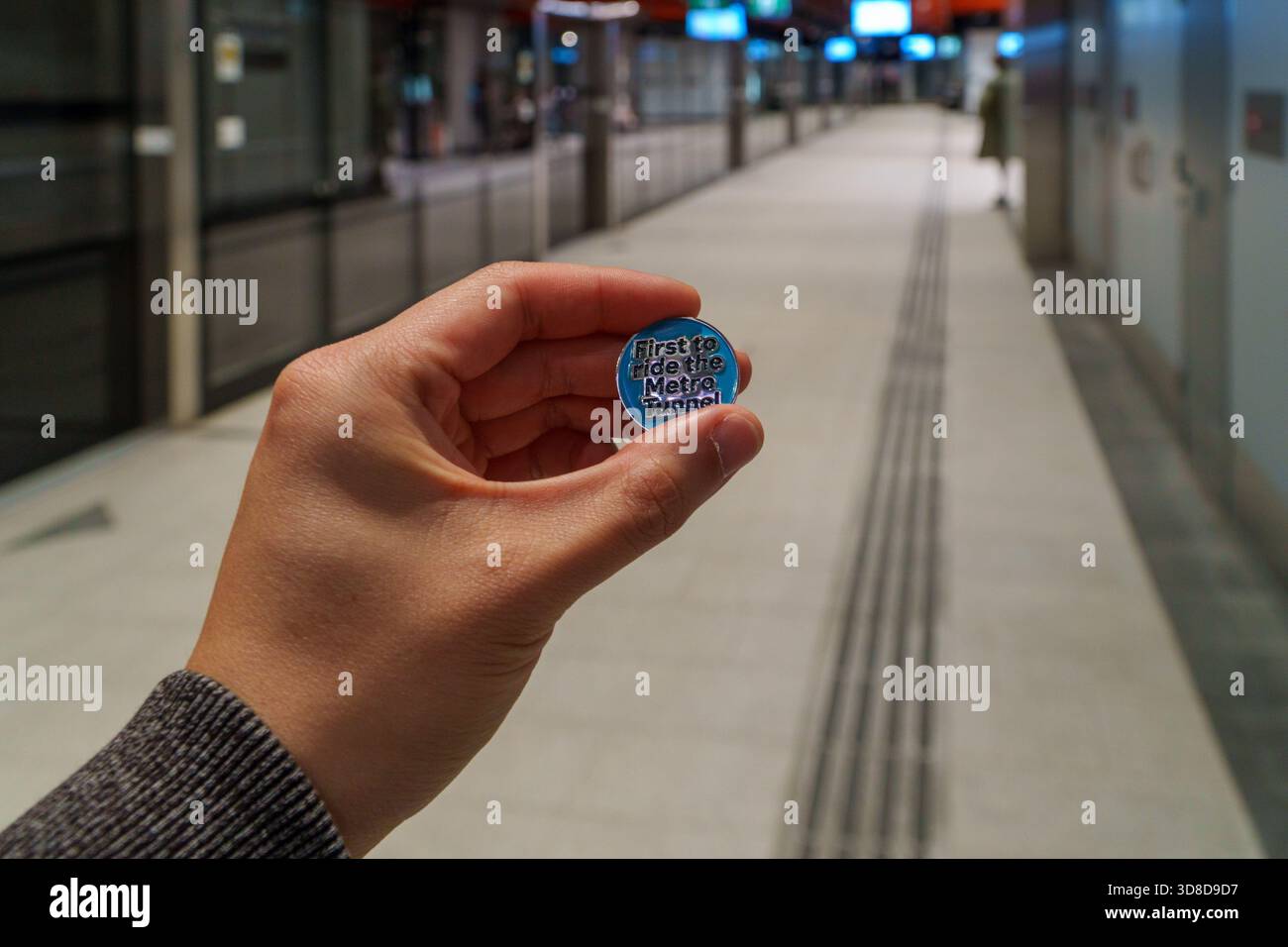 Melbourne, Victoria, Australia. 30 novembre 2025. - La mano Di Una persona mostra in modo prominente un distintivo blu, con l'iscrizione 'First to ride the Metro Tunnel!', agains Foto Stock