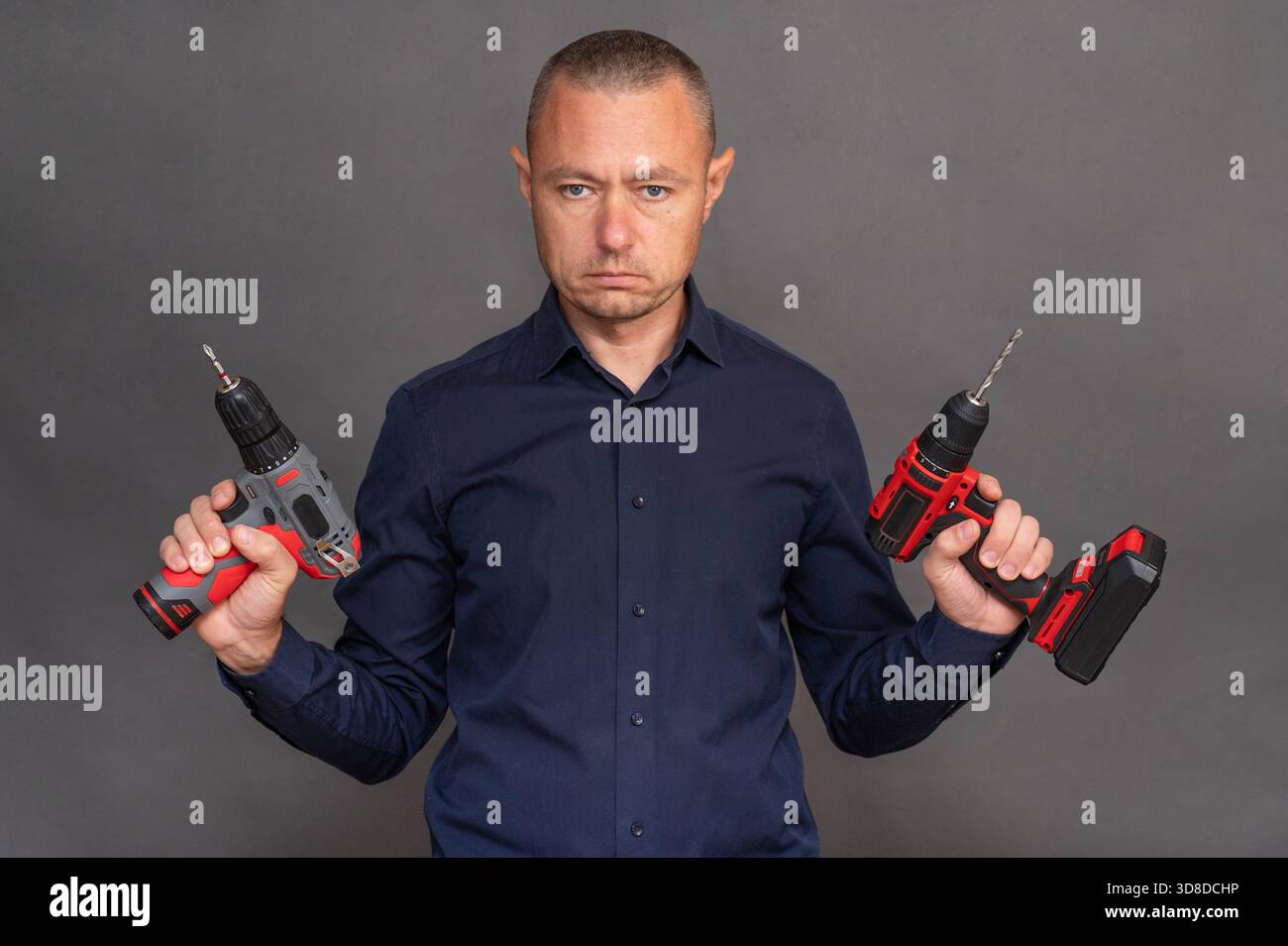 man possiede due cacciaviti cordless, dimostrando il design ergonomico e la funzionalità degli utensili. Utensili elettrici moderni pronti per vari progetti fai-da-te o. Foto Stock