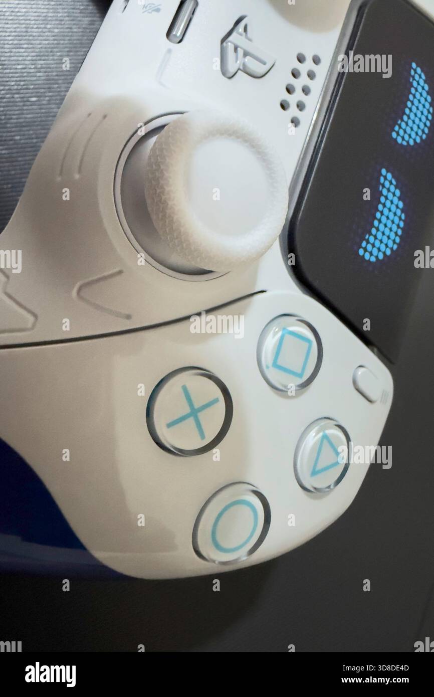 Doha, Qatar - 28 novembre 2025: Un giocatore sta giocando a Play Station 5 in casa, con la sua mano che tiene il joystick Dual Sense, il nuovo controller wireless. Foto Stock